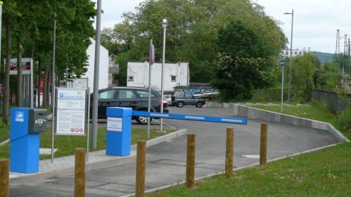 Einfahrt Parkplatz mit Schrankenanlage, parkende Autos.