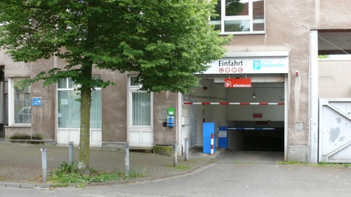 Einfahrt Tiefgarage mit Schrankenanlage, links Baum