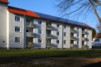 Saniertes, weißes Wohnhaus, Balkonseite, mit Wiese davor. Drei Wohnetagen. Auf dem Dach Photovoltaikanlage. Saniertes, weißes Wohnhaus, Balkonseite, mit Wiese davor. Drei Wohnetagen. Auf dem Dach Photovoltaikanlage.