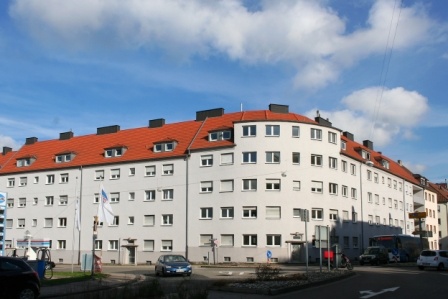 Halbrundes Wohnhaus mit fünf Etagen an befahrener Straße-. Helle Fassade. 
