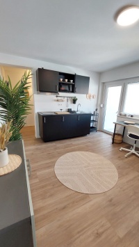 schwarze Miniküche mit rundem Sisalteppich in beige davor.