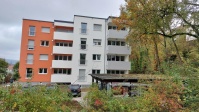 Blick auf Moltkestraße 5 während der Sanierung viergeschossiges Wohnhaus mit Flachdach, Balkonseite, während Umbau. Fassade braun und weiß.