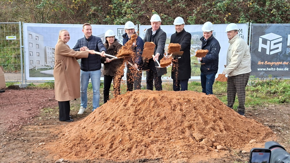 Spatenstich am 7.11.2025 (v.l.n.r.).: Kira Braun, Sascha Haas (jeweils MdL), Doris Woll (SIKB), Minister Reinhold Jost, Geschäftsführer Robert Tucovic, Oberbürgermeister Uwe Conradt, Baudezernent Patrick Berberich, Bezirksbürgermeister Ralf-Peter Fritz. Acht Personen mit Spaten hinter einem Sandhügel.