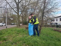 2 Männer mit Warnwesten, Greifzangen und Müllsack auf Grünfläche 