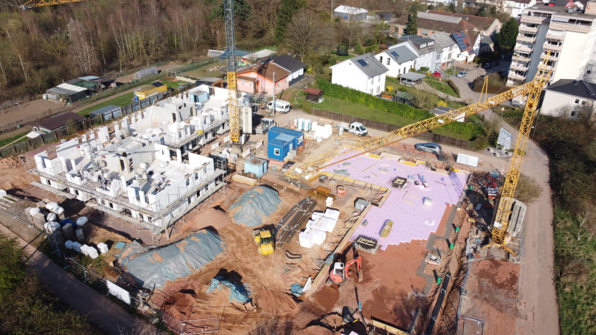 Drohnenaufnahme der Baustelle mit 1. Gebäude links mit Erdgeschoss und Mauern 1. Etage, rechts Bodenplatte 2. Gebäude.