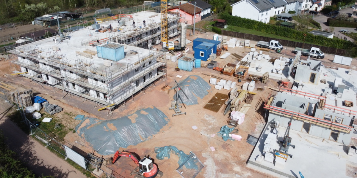 Luftbildaufnahme der Baustelle; linker Baukörper mit 2 Etagen und Gerüst, rechter Baukörper Bodenplatte und teilweise gemuert